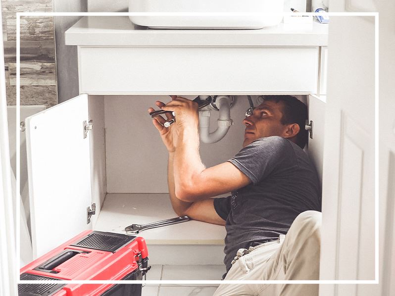 Plumber working under sink