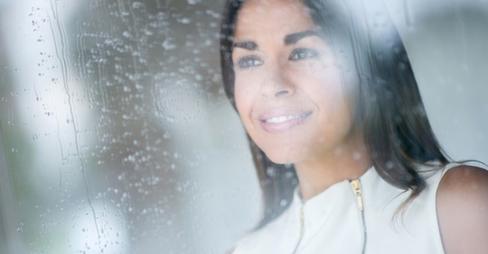 woman looking out foggy wet window