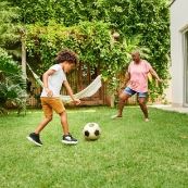 A child and adult playing soccer in a yard