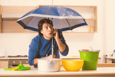 Man standing under a leak with an umbrella.
