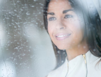 woman looking out foggy wet window