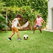 A child and adult playing soccer in a yard