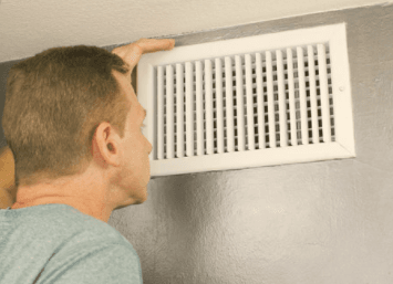 man inspecting air vent