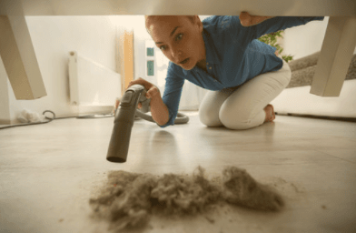 woman vacuuming dust under furniture